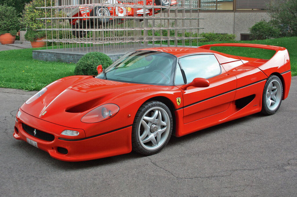 Red F50 parked in front of a lawn with a art sculpture in the background