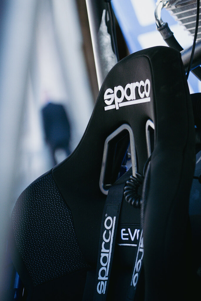 Black Sparco race seat with harness inside of a car