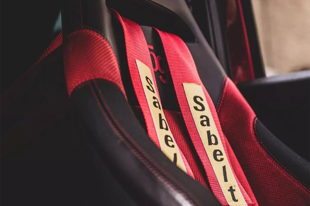 Red and yellow Sabelt race harness paired with a red and black aftermarket seat inside of a car