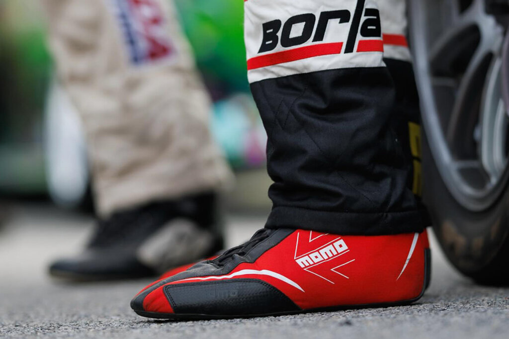 Red MOMO race shoes closeup next to a tire
