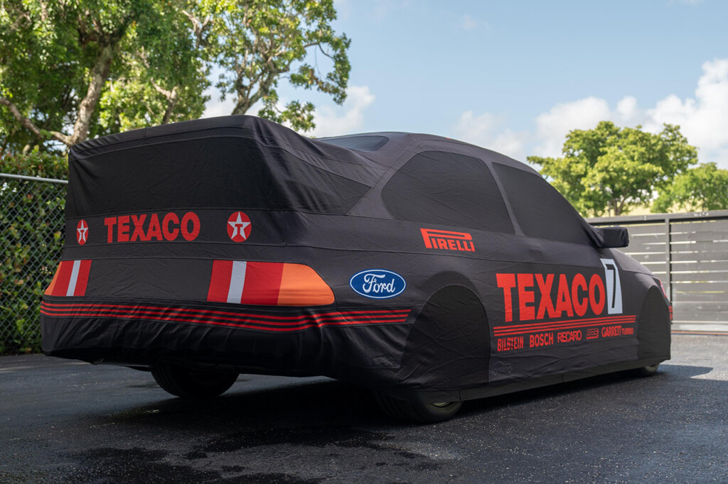 Texaco car cover over a car with trees and blue sky in background