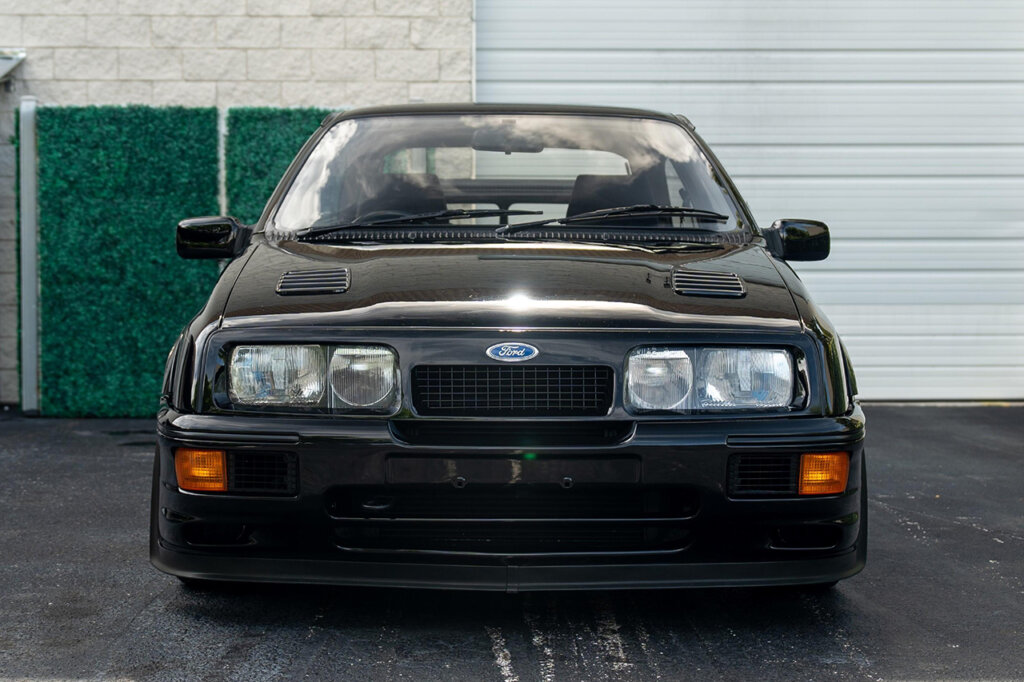 Black Sierra Cosworth parked in front of a white brick wall and garage door
