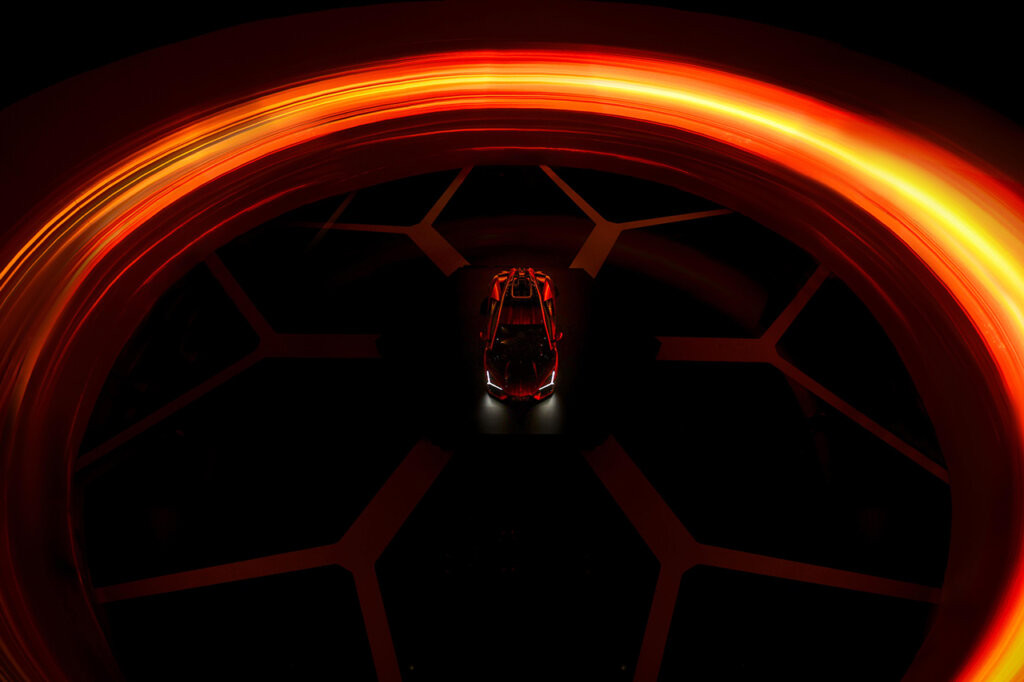 Red Lamborghini in the center of a stage with an orange halo surrounding the car