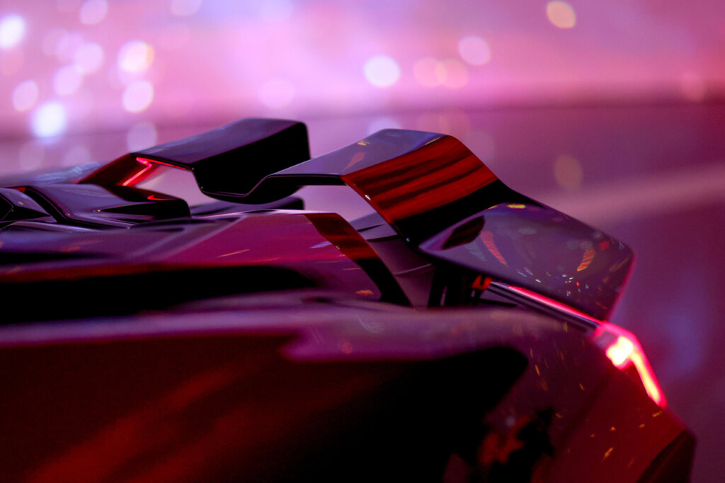 Closeup of a Lamborghini Revuelto Opera Unica with aggressive rear spoiler and angular body lines of the car with pinkish red background behind the car.