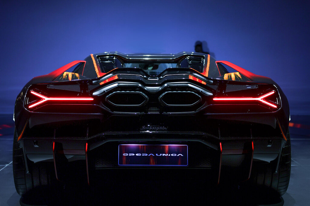 Red Revuelto car with LED rear taillights with vents and exhaust showing and a blue background behind the car.