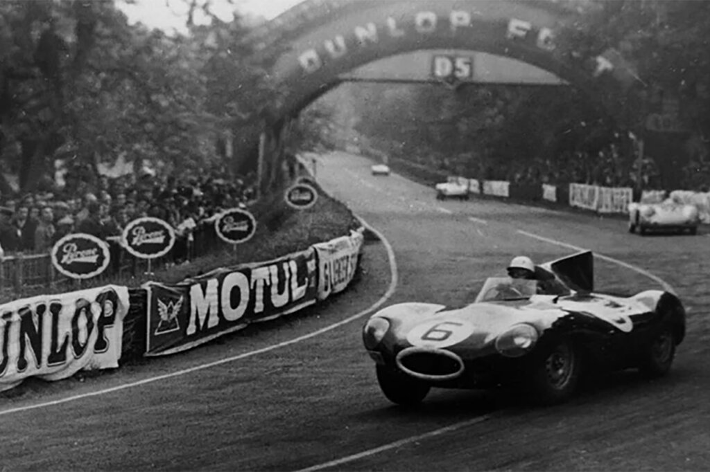 Black and white photo of a race car going through the Dunlop Curve during the 24hrs of Le Mans race.
