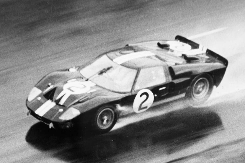 Black and white photo of the Ford GT40 driving on a wet race course.