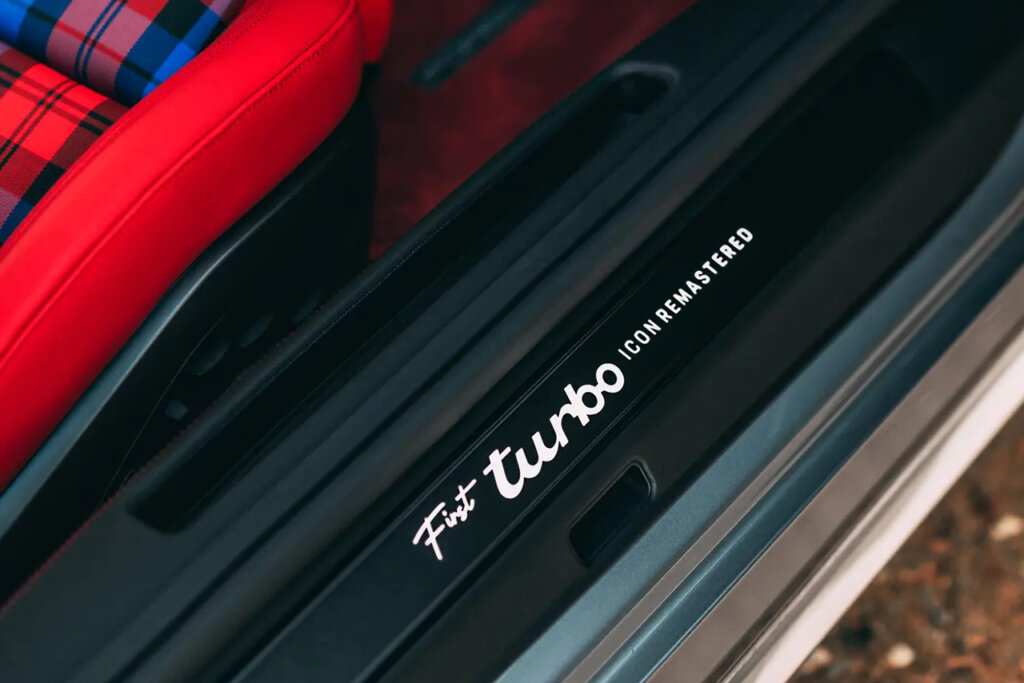 Words on black plastic door card that says First Turbo Icon Remastered with red and plaid red and blue upholstered seat