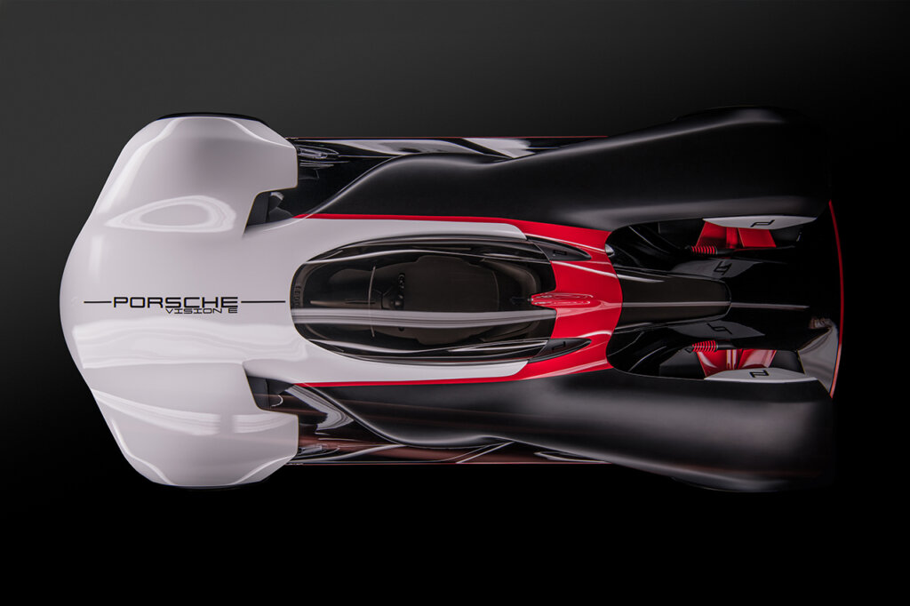 White and black Porsche Vision E concept car with red accent trim shot form the top showing the single cockpit car on a black background.