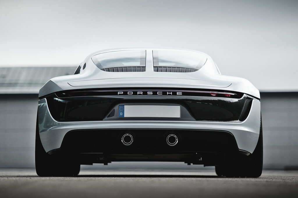Rear shot of a Porsche Le Mans Living concept car parked pointing away from the camera with grey clouds in the background and barrier waist high.