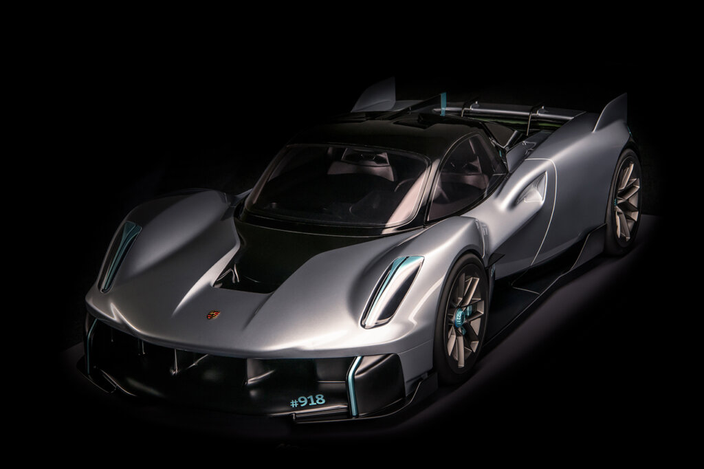 Silver Porsche Vision 918 RS shot in a dark room with light reflecting off of the hood, front windshield and headlights.