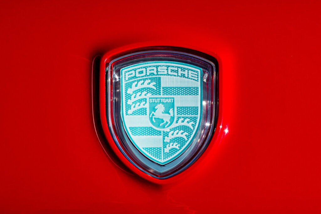 Light blue Porsche crest mounted onto a red panel