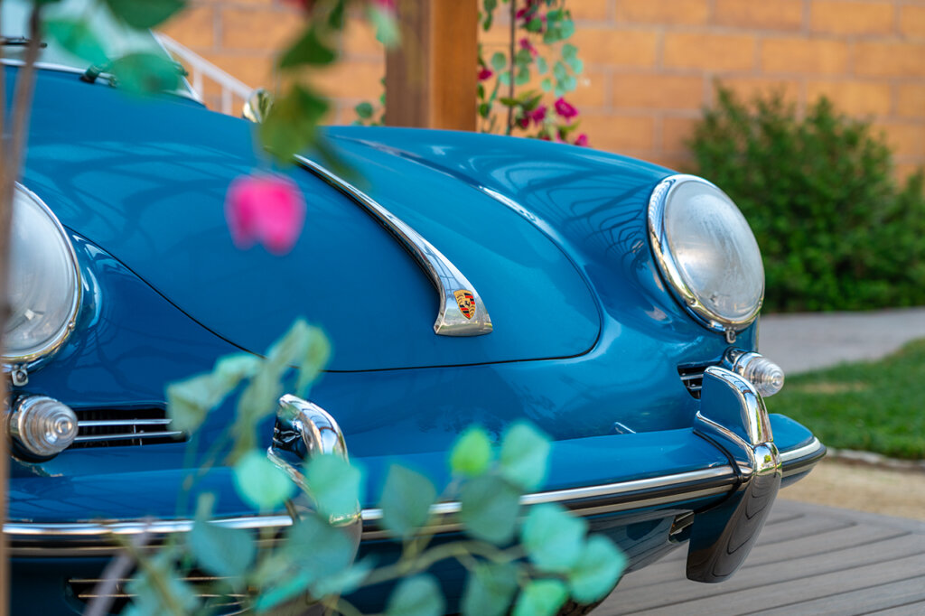 Blue Porsche 356 closeup of front end with flowers in front of the car