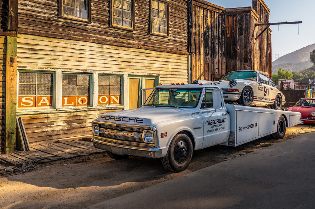 White 911 sitting on a tow bed of a Chevrolet C10 with the word Porsche on the front end