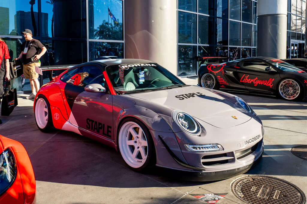 Rohana Wheels Nardo grey with red Porsche 911 parked outside next to a concrete column next to other cars at SEMA 2024