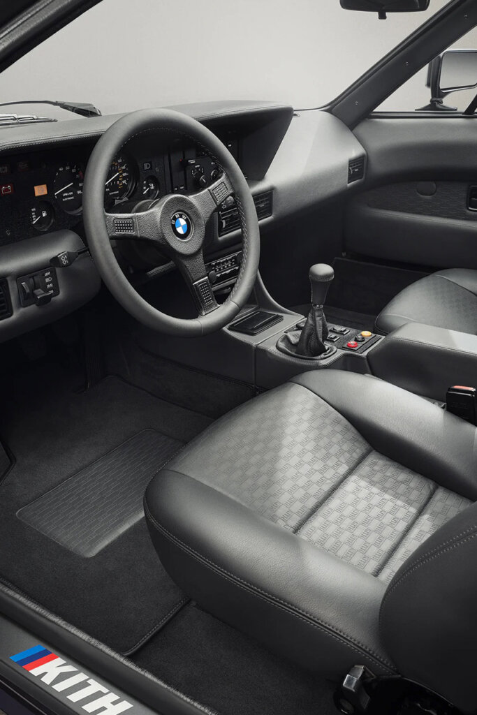 Black leather custom interior of a Techno Violet BMW M1 E26 by Ronnie Fieg & KITH with the KITH logo in the left corner on the door trim.