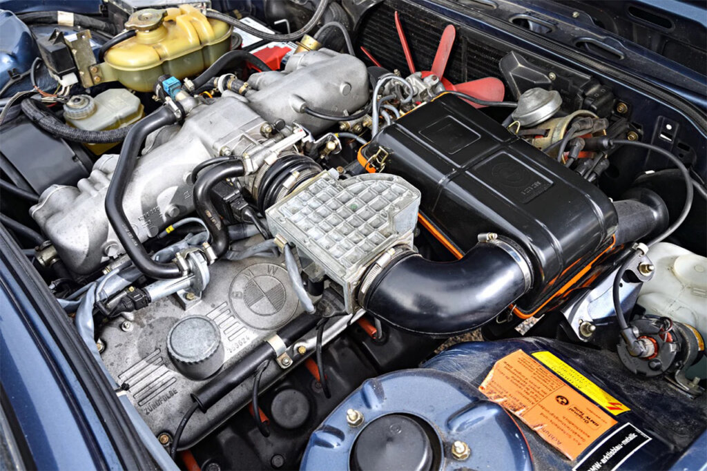 3.5L Inline-6 inside of a blue BMW with wires and colored plastics all in the engine bay area.