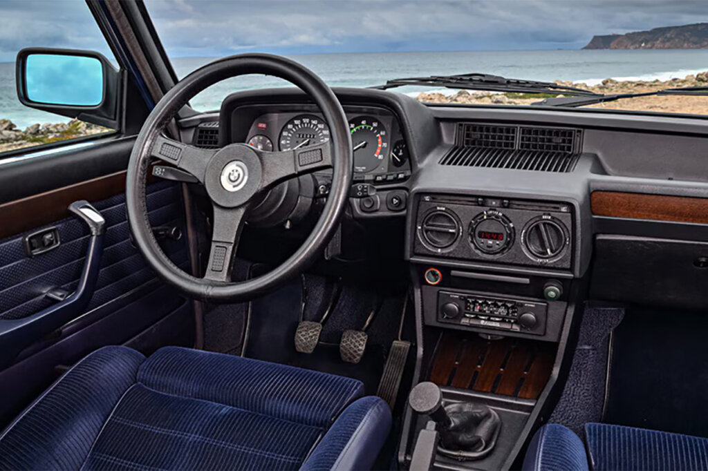 Black interior with blue suede seats and wooden panelled dashboard.