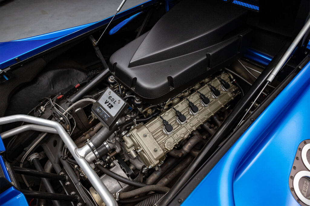 V12 engine with carbon fiber intake manifold on top of the engine with tubes and wires everywhere inside of a Blu Monterey Diablo GTR.
