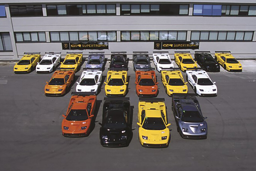 Rows of Lamborghini Diablo GTR's next to one another some Yellow, Orange, White, Silver. All staged in front of a building with banners that say GTR Supertrophy.