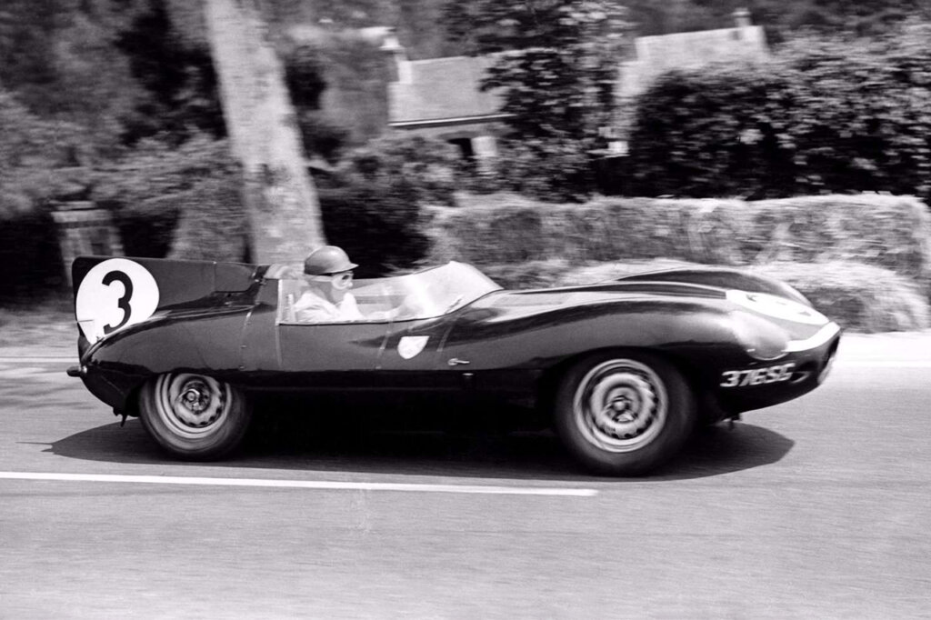 Black and white photo of a man behind the wheel of a racecar during a Le Mans race.