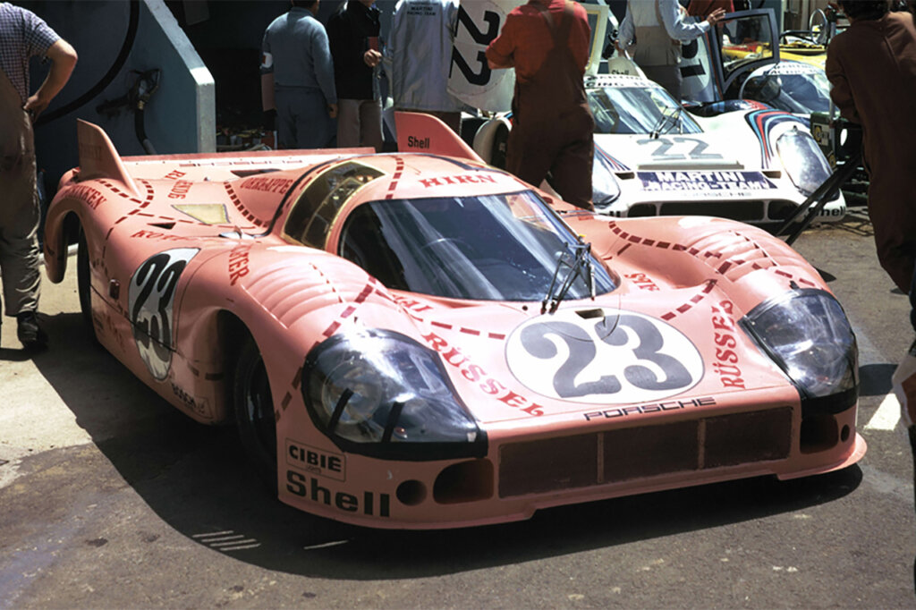 Pink Pig race car livery on a Porsche 917 parked with several people standing around the car.