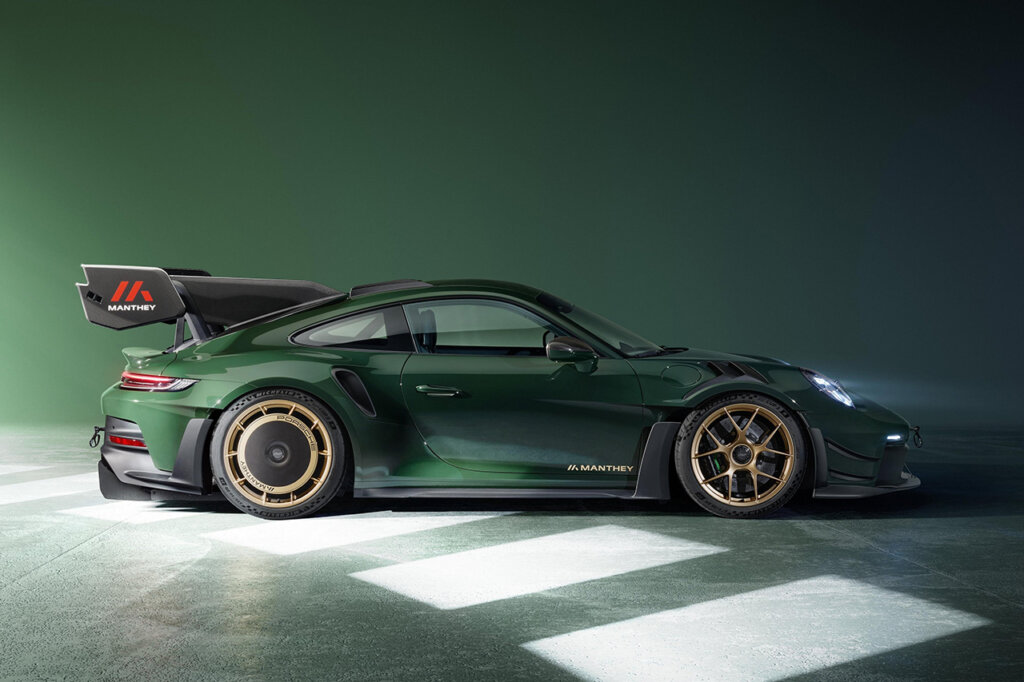 Side profile of a green Porsche 911 GT3 RS parked in a green room with concrete floor with light streak and rectangular shapes on the floor.