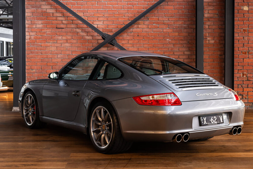 Silver Porsche 997 carrera S parked in a showroom floor with a brick wall and wood flooring