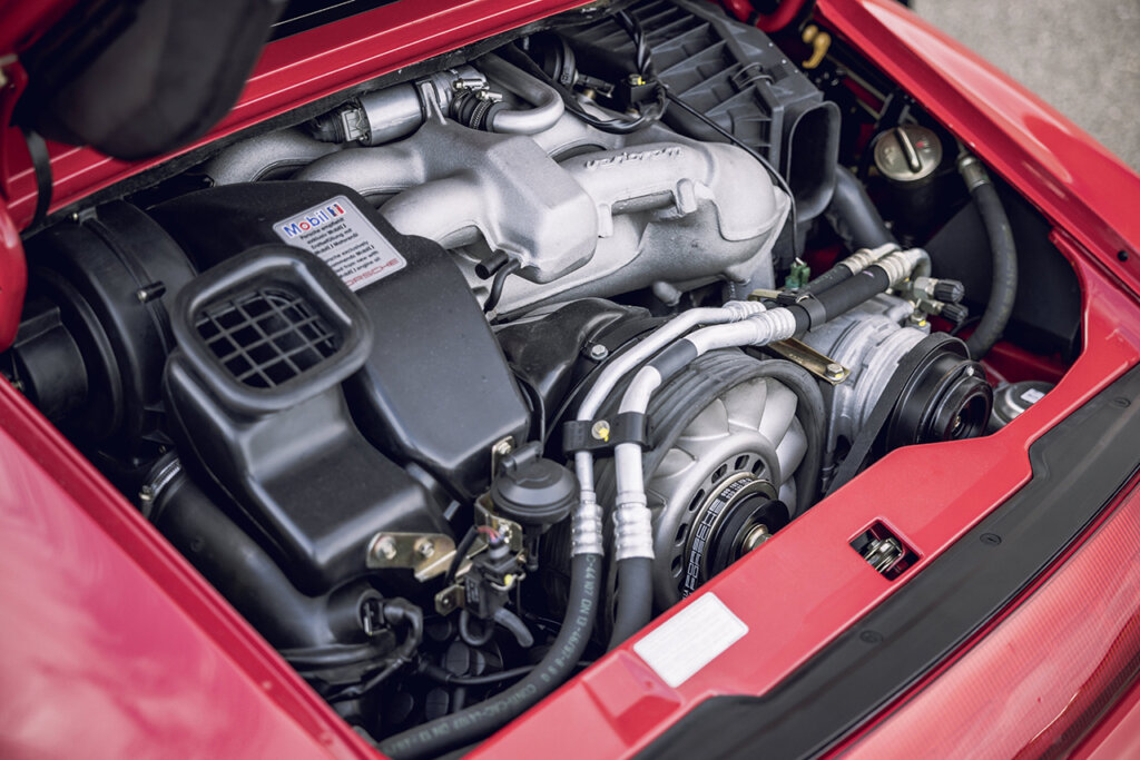 Engine bay with metal and black parts interconnected inside of a pink 993