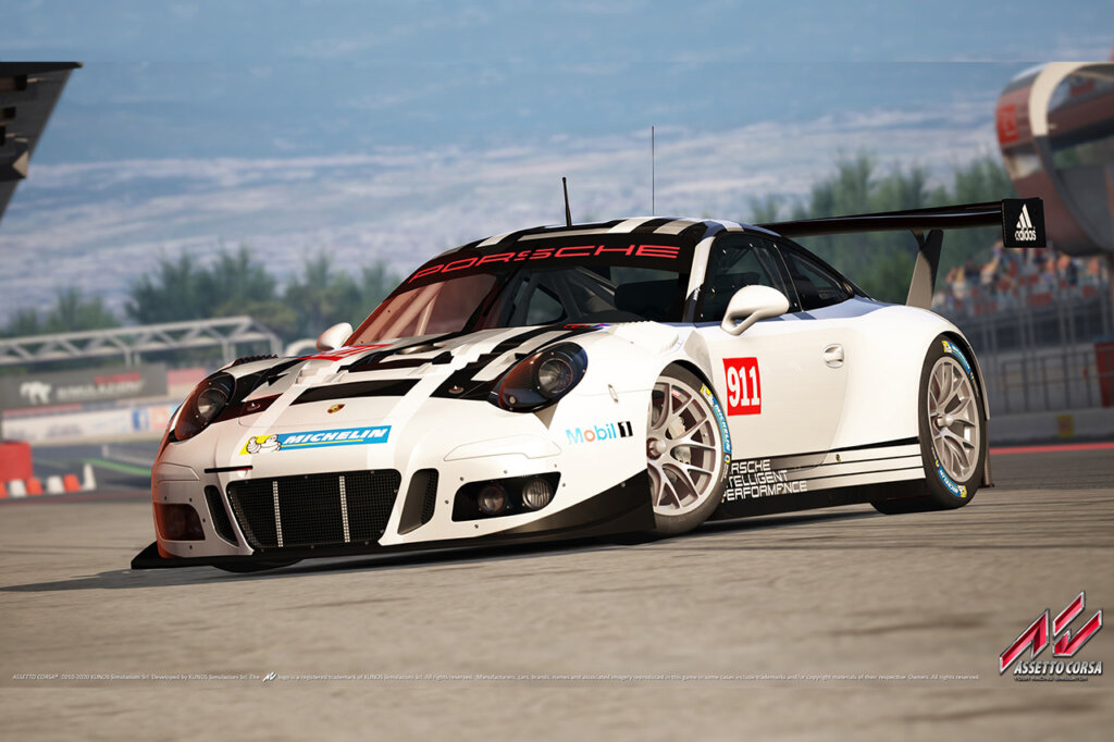 White Porsche 911 with large rear mounted spoiler and aero parts parked at an angle with blue sky in background.