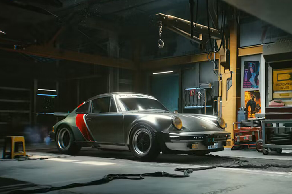 Silver Porsche 911 930 Turbo with red stripe in a garage with machine equipment and tools all over the place.