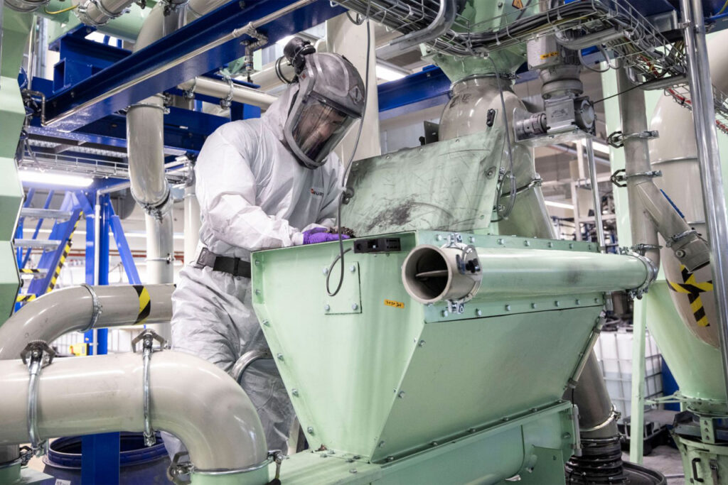 Man in hazmat suit recycling parts at Porsche