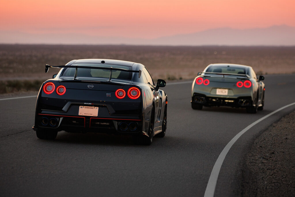 Rear of Nissan nismo r35 gt-r and gray nissan r35 gt-r driving during sunset