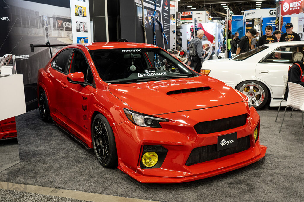 red dustiinw subaru wrx in aeroluxe booth at sema 2025 central hall