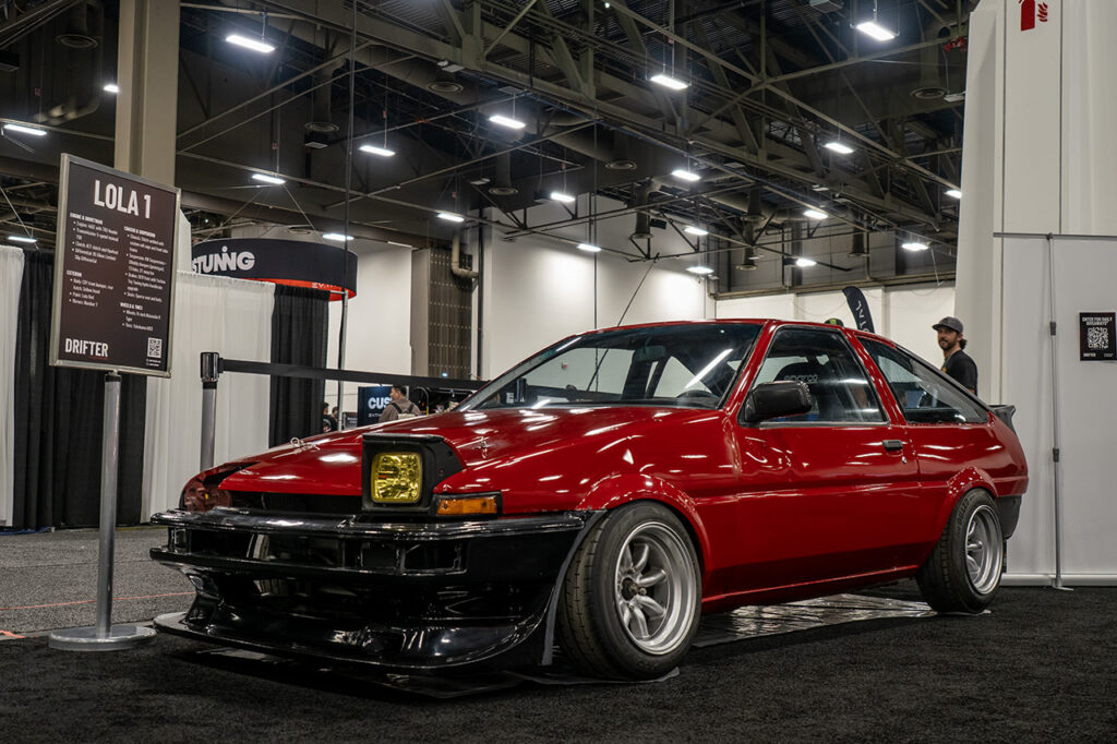red and black toyota ae86 trueno lola 1 in drifter booth at sema 2025 central hall